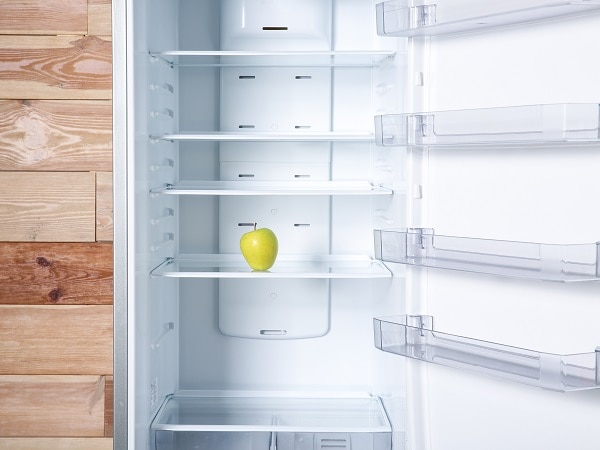 open refrigerator with a single apple in it