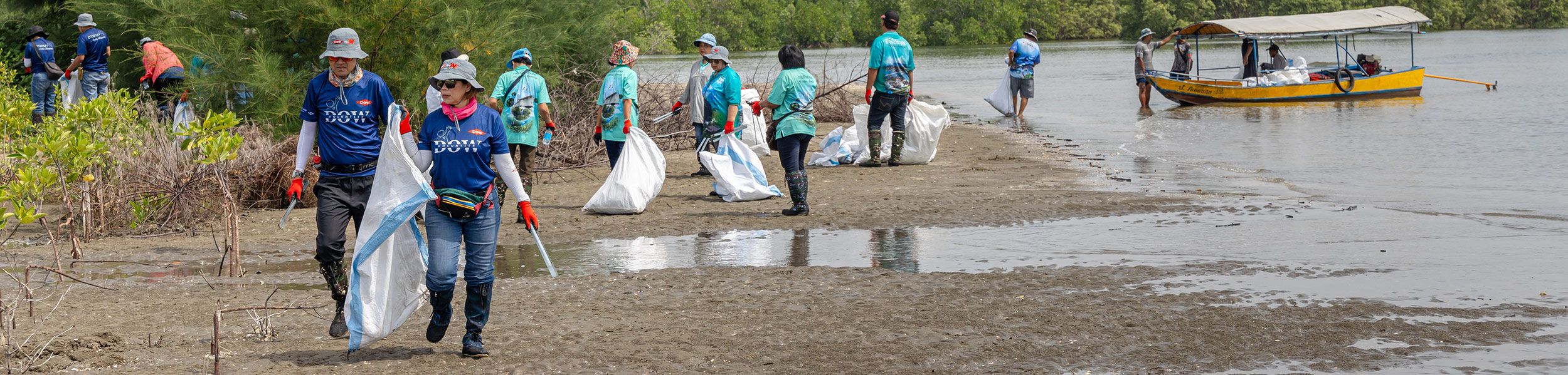 group of people cleaning up trash off beach